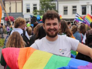 Thijmen wappert met een regenboogvlag bij de Zwolse Pride.